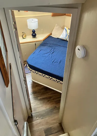 New Moon Yacht Photos Pics Cozy cabin interior of 1996 Hatteras 42 CPMY with blue bedding and wooden flooring.