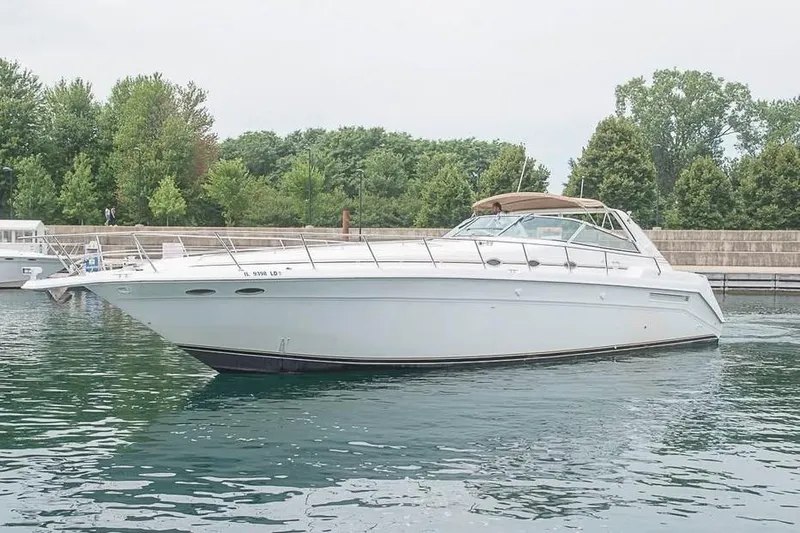  Yacht Photos Pics 1998 Sea Ray 500 Sundancer yacht on calm water near a lush shoreline.