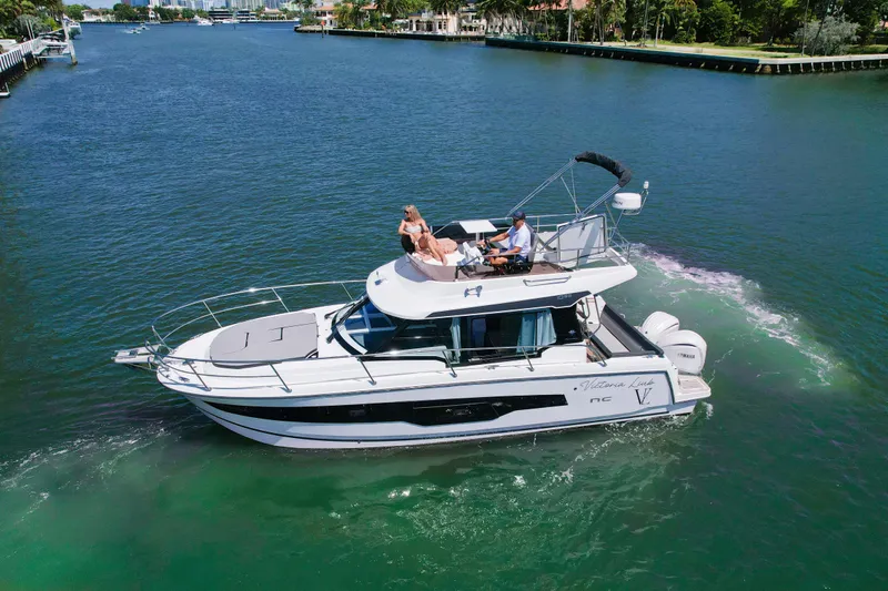  Yacht Photos Pics 2024 Jeanneau NC1095 Fly cruising on a scenic waterway with passengers enjoying the view.