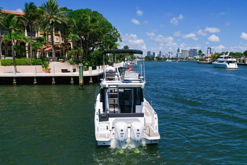  Yacht Photos Pics 2024 Jeanneau NC1095 Fly cruising in a scenic waterfront setting with city skyline.