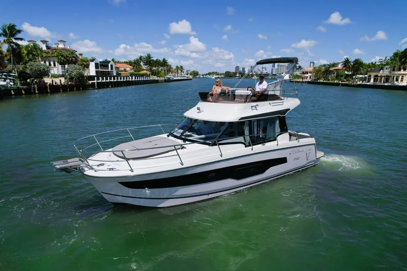  Yacht Photos Pics 2024 Jeanneau NC1095 Fly cruising on a scenic waterway under a clear blue sky.