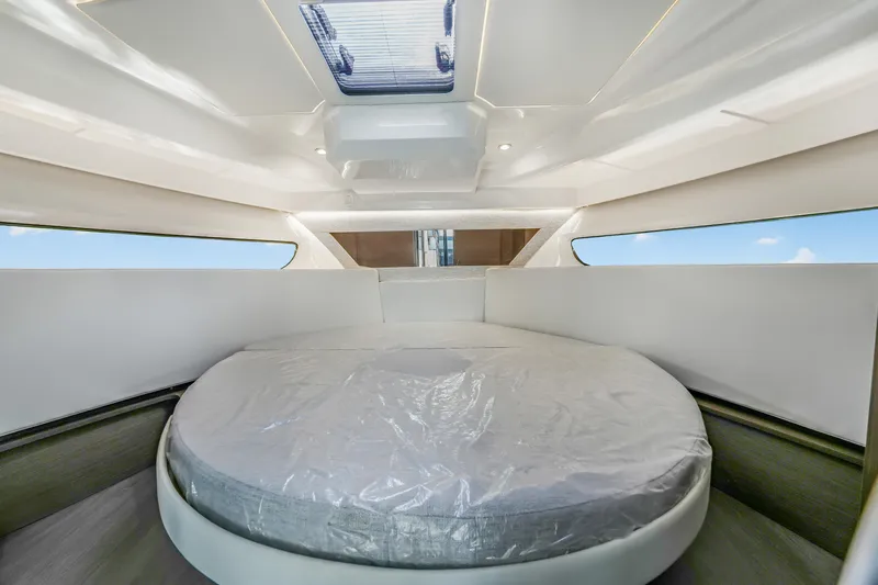  Yacht Photos Pics 2024 Jeanneau NC1095 Fly cabin interior with round bed and skylight.