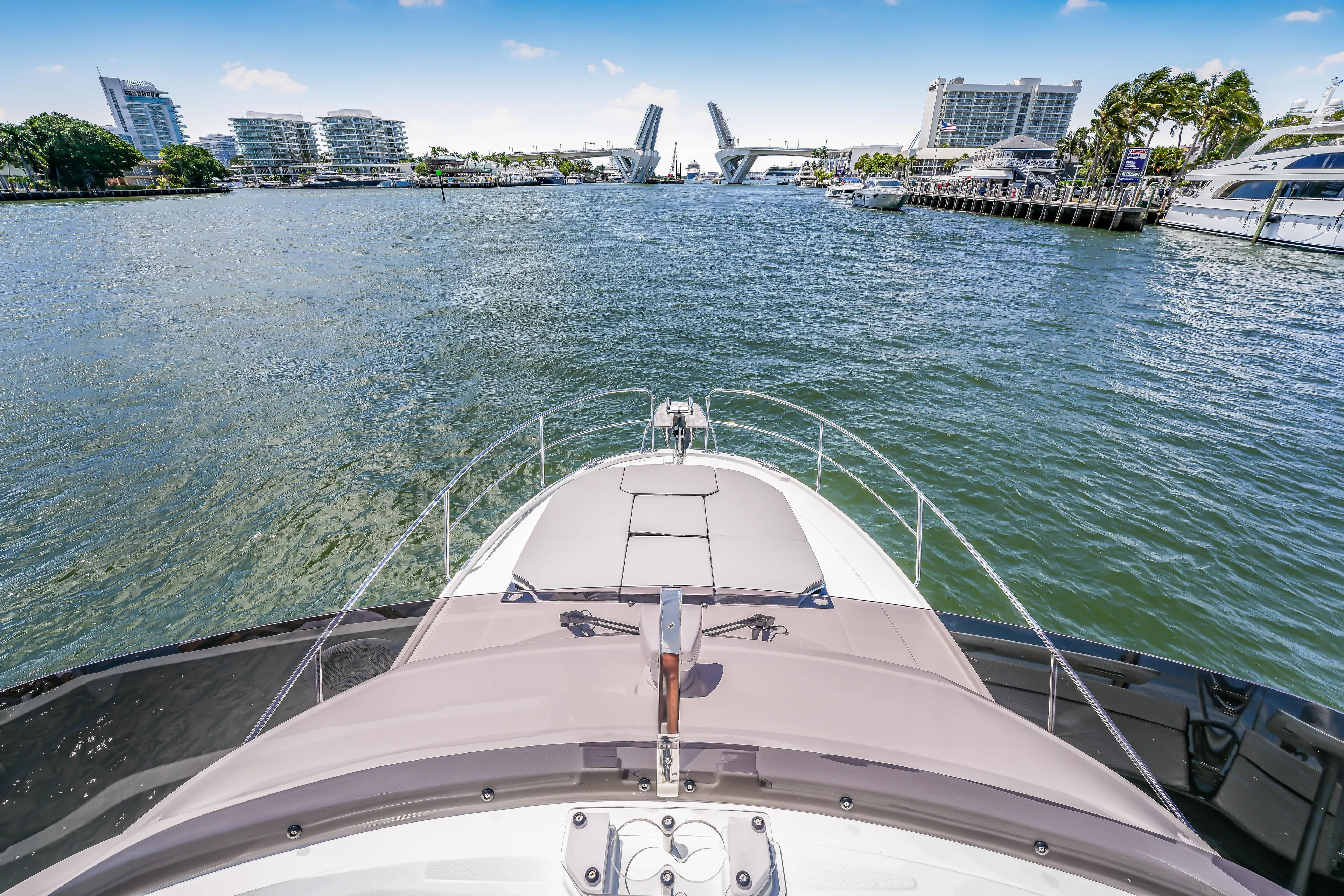  Yacht Photos Pics 2024 Jeanneau NC1095 Fly yacht cruising towards an open drawbridge in a city harbor.