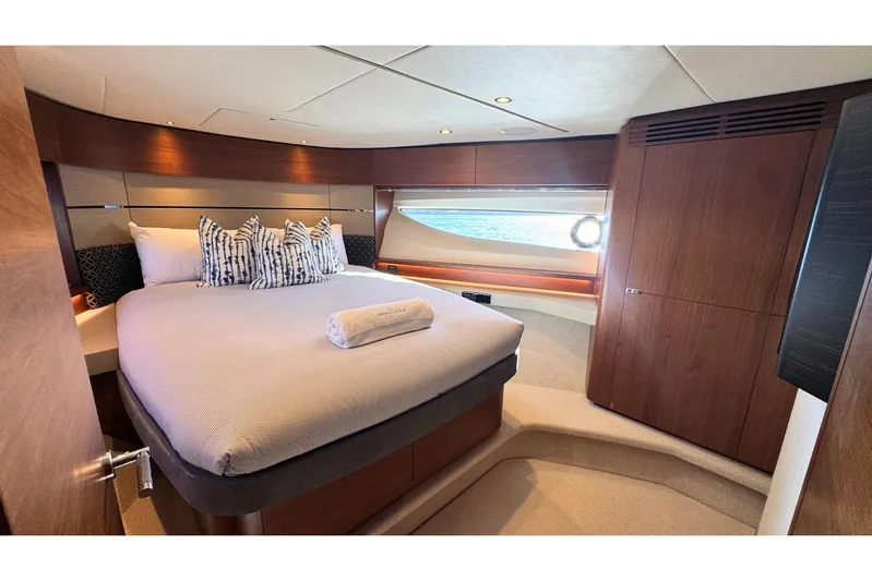B III Yacht Photos Pics Luxurious bedroom interior of 2021 Princess S62 yacht with elegant wood finishes and cozy bedding.