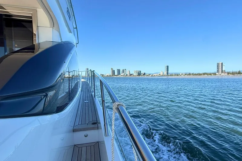 B III Yacht Photos Pics Luxurious 2021 Princess S62 yacht cruising near a coastal city skyline.