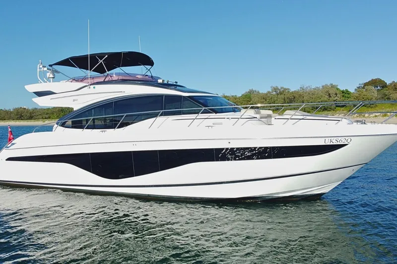 B III Yacht Photos Pics 2021 Princess S62 yacht cruising on a sunny day near a shoreline.