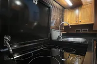 Modern kitchen in 2007 Trader 42 HT yacht with stovetop, sink, and wooden cabinets.