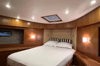 Luxurious cabin interior of 2007 Trader 42 HT yacht with wood paneling and cozy bedding.