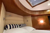 Luxurious cabin interior of 2007 Trader 42 HT yacht with elegant wood paneling and cozy bedding.
