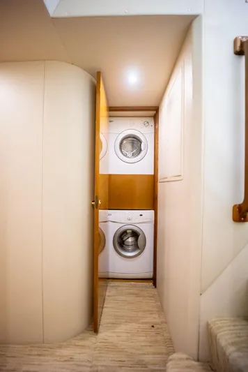 Killin Time Yacht Photos Pics Laundry area inside 2003 Viking 65 Convertible Enclosed Bridge yacht, featuring stacked washer and dryer.