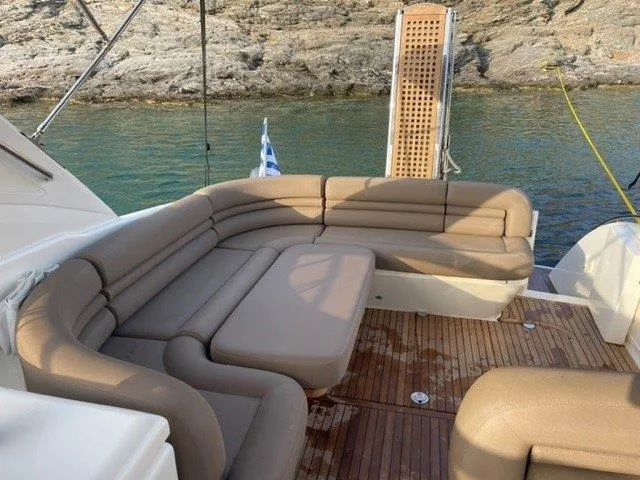  Yacht Photos Pics Luxurious 2006 Princess V42 yacht with spacious beige seating on deck, near rocky shoreline.