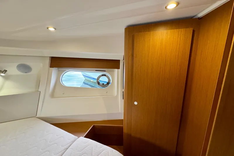  Yacht Photos Pics 2025 Beneteau Swift Trawler 35 cabin interior with wooden finishes and porthole window.