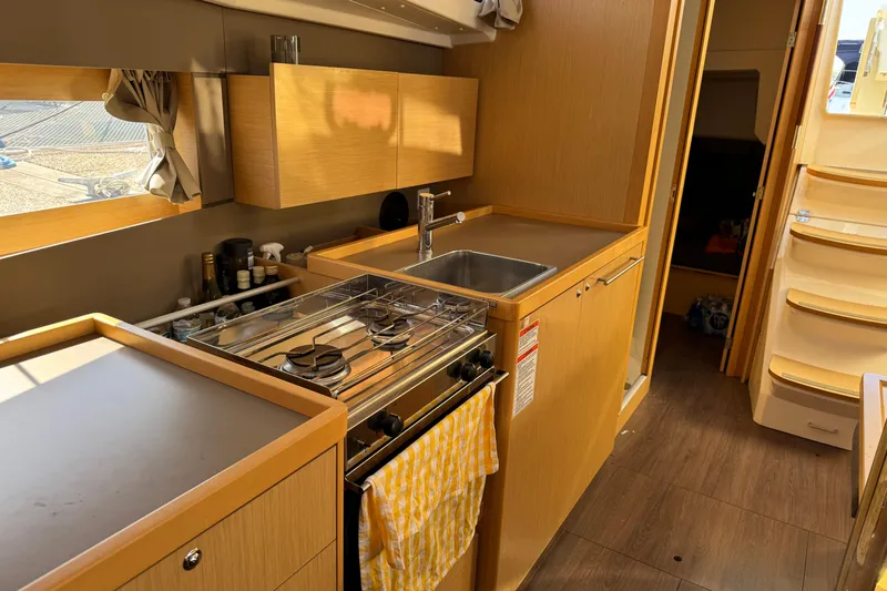 Moonraker Yacht Photos Pics Interior of 2014 Beneteau Oceanis 38 yacht kitchen with stove, sink, and wooden cabinetry.