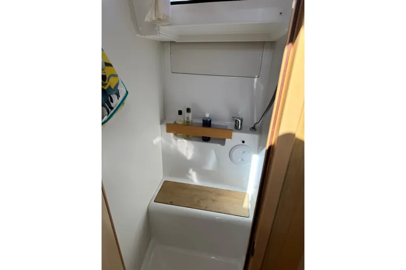 Moonraker Yacht Photos Pics Beneteau Oceanis 38 (2014) bathroom with shower, wooden seat, and toiletries shelf.