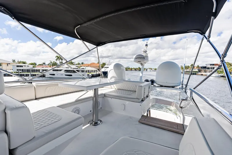 Liquid Asset Yacht Photos Pics 2010 Lazzara 78 Fly yacht interior with seating and table, under a canopy, by the water.