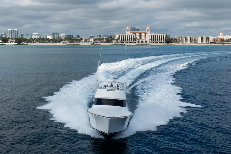 La Barca Yacht Photos Pics 2024 Viking 68 Convertible yacht cruising near a coastal city skyline.
