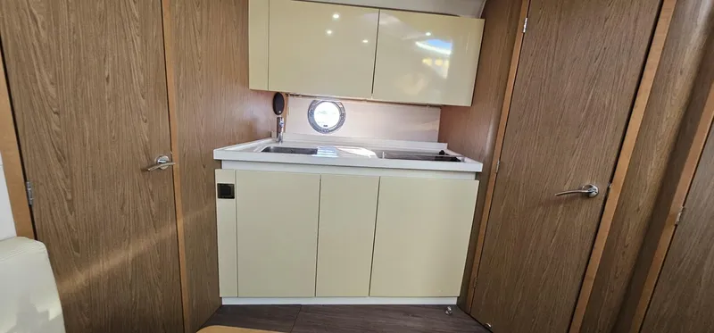 Mambo Italiano Yacht Photos Pics Interior of 2015 Beneteau 38 Gran Tourismo yacht, featuring a compact kitchenette with wood accents.
