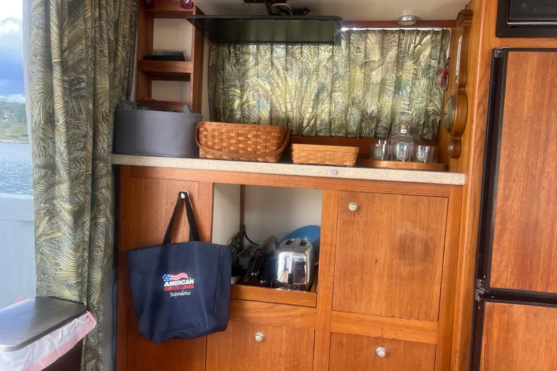 Beryl W Yacht Photos Pics Interior of 2001 Mainship 390 Trawler with wooden cabinets and decorative curtains.