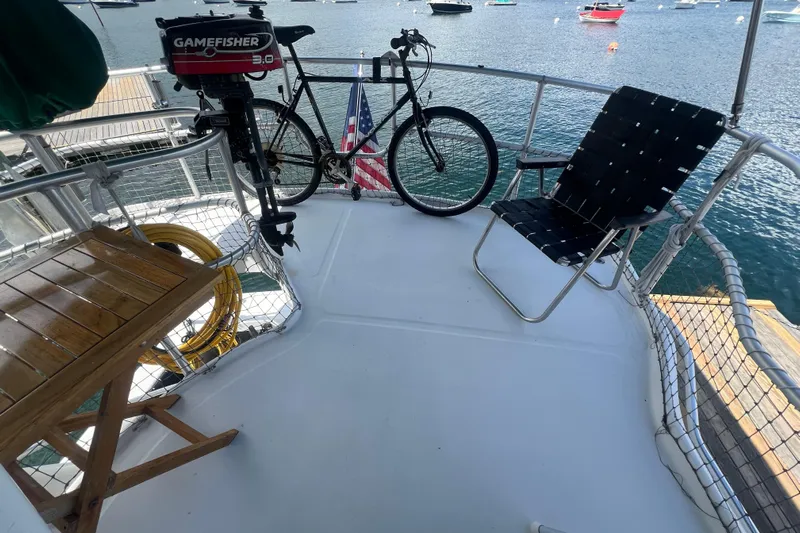 Beryl W Yacht Photos Pics Deck of 2001 Mainship 390 Trawler with chair, bicycle, and motor overlooking water.