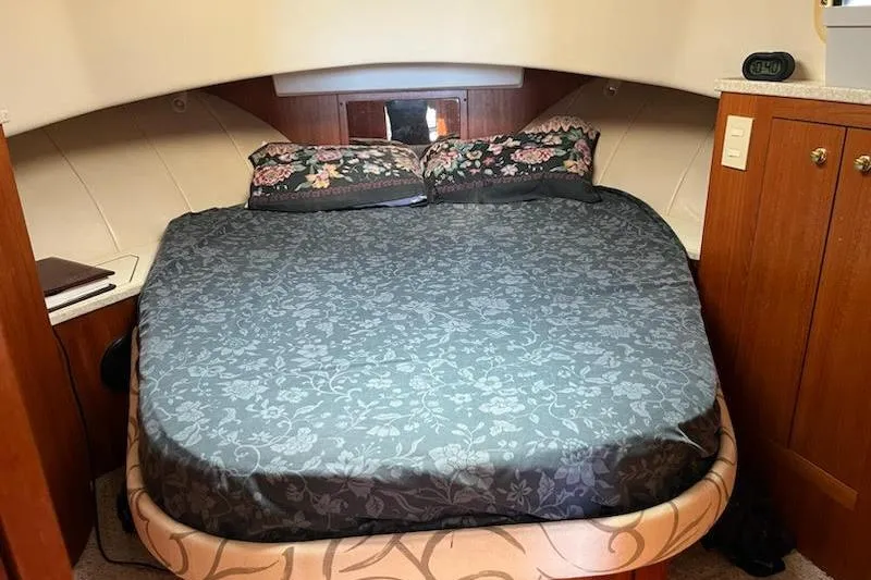 Beryl W Yacht Photos Pics Cozy bedroom in 2001 Mainship 390 Trawler with floral bedding and wooden cabinetry.