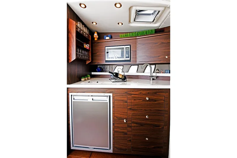  Yacht Photos Pics Manufacturer Provided Image: 2018 Rinker EX 370 boat kitchen with modern appliances and wooden cabinetry.
