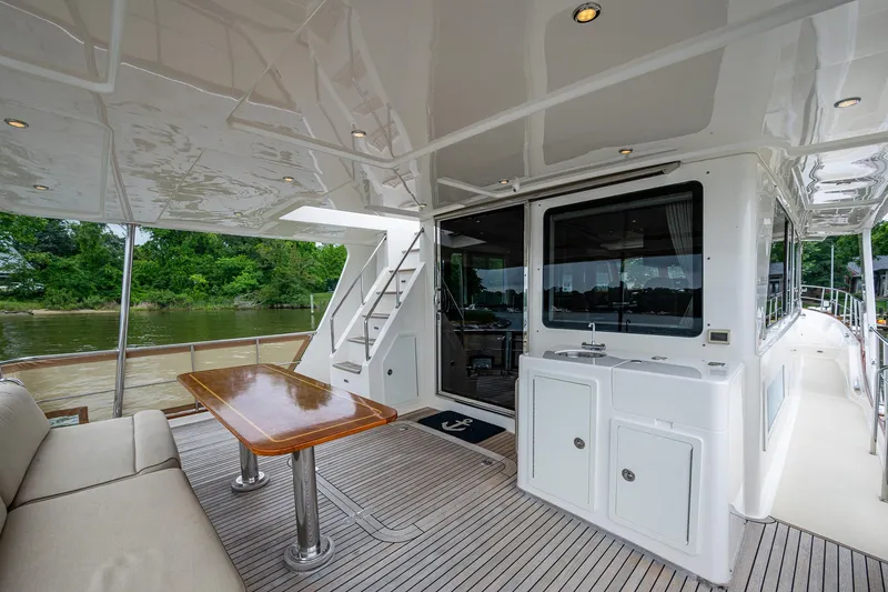 Venture Yacht Photos Pics Luxurious 2014 Grand Banks 54 Europa yacht deck with seating and table, near serene water.
