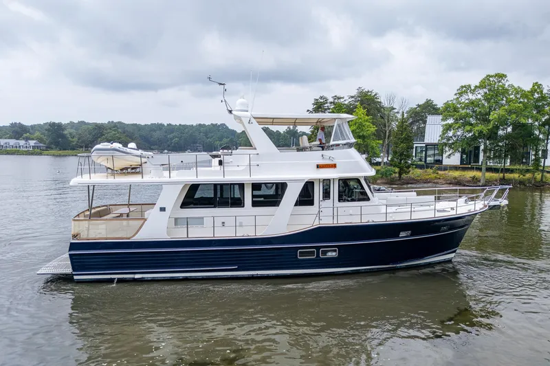 Venture Yacht Photos Pics 2014 Grand Banks 54 Europa yacht cruising on a calm river under cloudy skies.