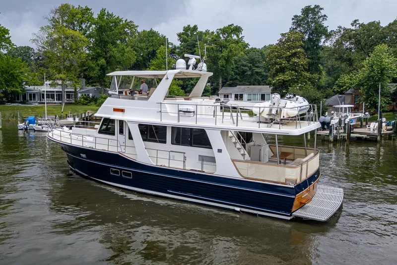 Venture Yacht Photos Pics Grand Banks 54 Europa 2014 yacht docked on a serene river with lush greenery.