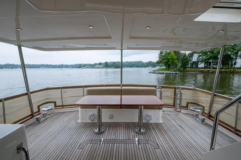 Venture Yacht Photos Pics Grand Banks 54 Europa 2014 yacht deck with table, overlooking serene lake view.