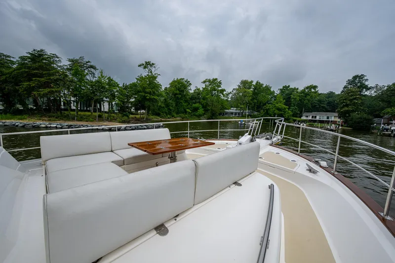 Venture Yacht Photos Pics Luxurious 2014 Grand Banks 54 Europa yacht deck with seating and table, surrounded by scenic waterway.