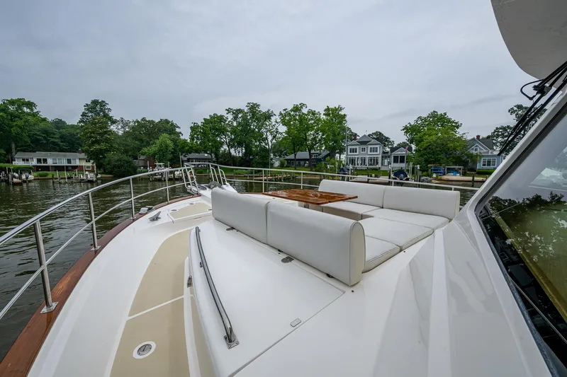 Venture Yacht Photos Pics 2014 Grand Banks 54 Europa yacht with spacious deck and seating, docked near waterfront homes.