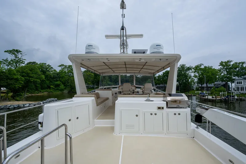 Venture Yacht Photos Pics 2014 Grand Banks 54 Europa yacht deck with seating and equipment, docked by lush greenery.