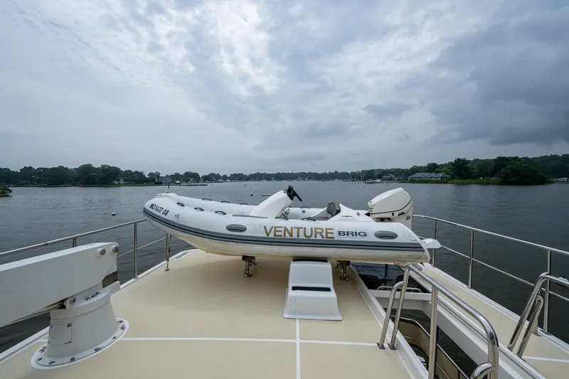 Venture Yacht Photos Pics 2014 Grand Banks 54 Europa yacht with a dinghy on deck, overlooking a serene waterway.