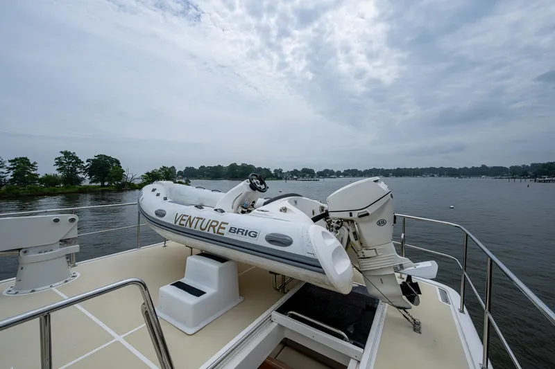 Venture Yacht Photos Pics 2014 Grand Banks 54 Europa yacht with a Venture Brig dinghy on deck, overlooking a serene waterway.