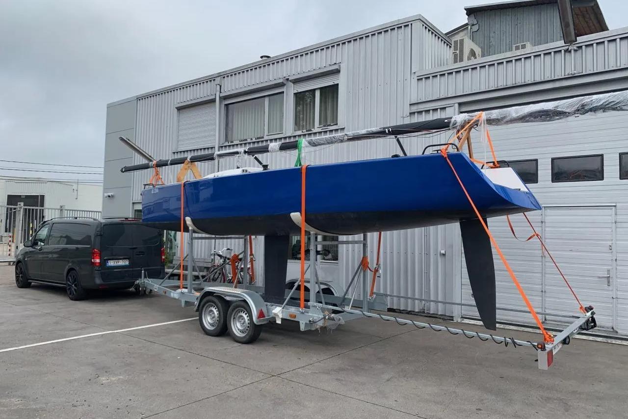 Blue Esse 850 LE sailboat on trailer, parked outside industrial building, 2020 model.