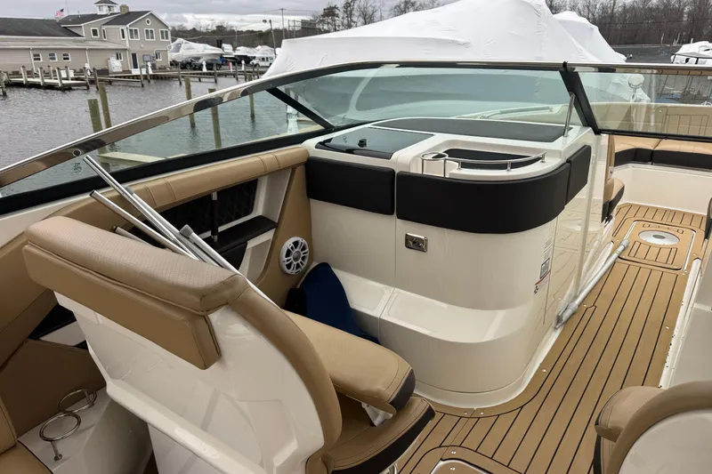  Yacht Photos Pics 2021 Sea Ray SLX 310 boat interior with tan seating and wood-style flooring at a marina.