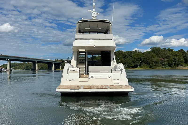  Yacht Photos Pics 2018 Sea Ray Fly 520 yacht on calm water, with scenic bridge and trees.