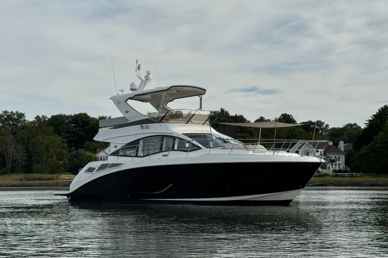  Yacht Photos Pics 2018 Sea Ray Fly 520 yacht on calm water, surrounded by trees and houses.