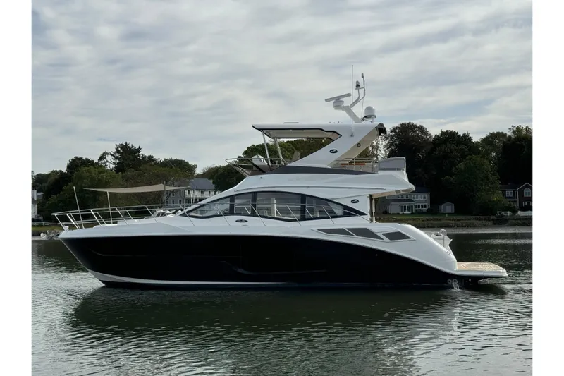 Yacht Photos Pics 2018 Sea Ray Fly 520 yacht on calm water, surrounded by trees and houses.