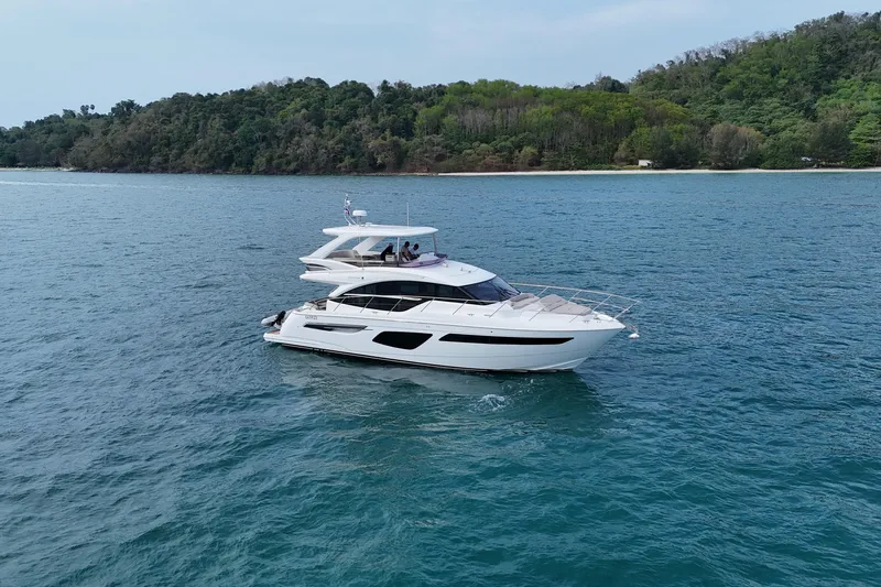 Lariel Yacht Photos Pics Luxurious 2020 Princess F55 yacht cruising on serene blue waters near a lush green coastline.