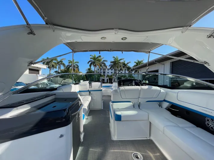  Yacht Photos Pics 2020 Formula 310 Bowrider interior with luxurious seating and canopy, set against a sunny backdrop.