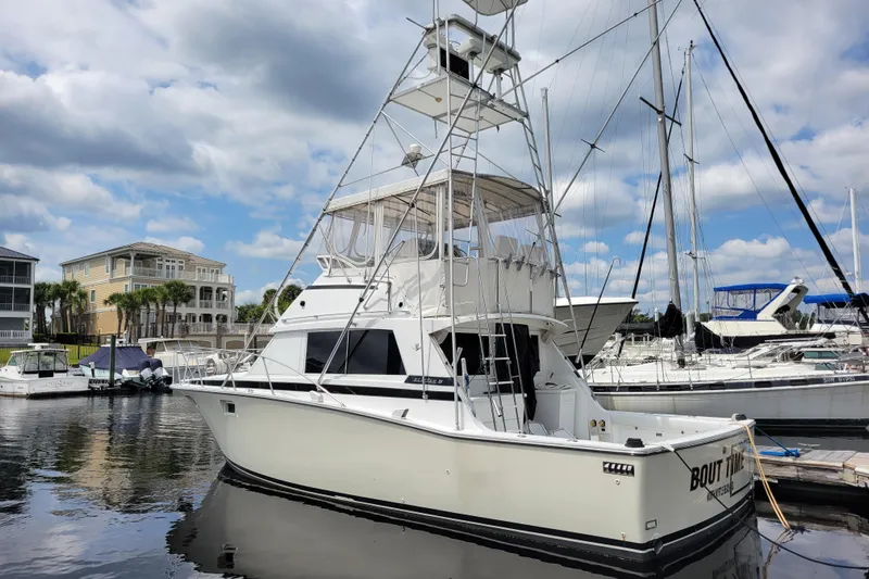 Bout Time Yacht Photos Pics 1979 Bertram 38 Convertible yacht docked at marina under cloudy sky.