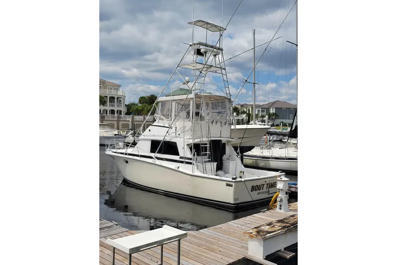 Bout Time Yacht Photos Pics 1979 Bertram 38 Convertible yacht docked at marina under cloudy sky.