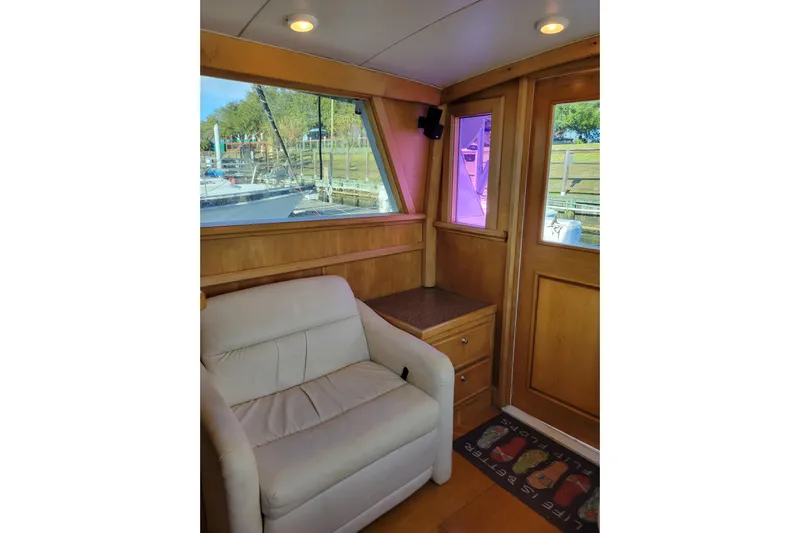Bout Time Yacht Photos Pics Interior of 1979 Bertram 38 Convertible yacht with white armchair and wooden paneling.