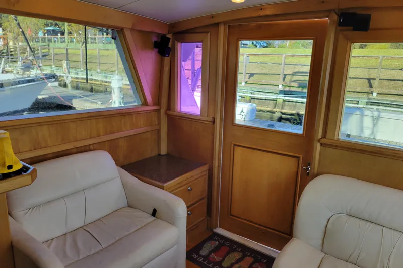 Bout Time Yacht Photos Pics Interior of 1979 Bertram 38 Convertible yacht with wood paneling and white seating.