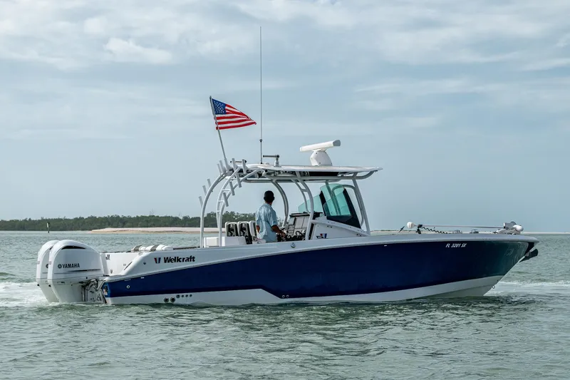  Yacht Photos Pics 2020 Wellcraft 302 Fisherman boat cruising on water with American flag.