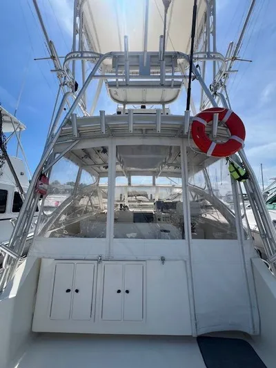 My Turn Yacht Photos Pics 2002 Carolina Classic 35 Express boat with tower and life preserver, docked under clear sky.