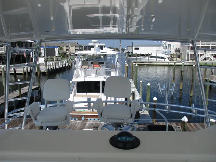 Slick Nickel Yacht Photos Pics Bertram 60 Convertible yacht, 2000 model, docked at a marina with scenic waterfront view.