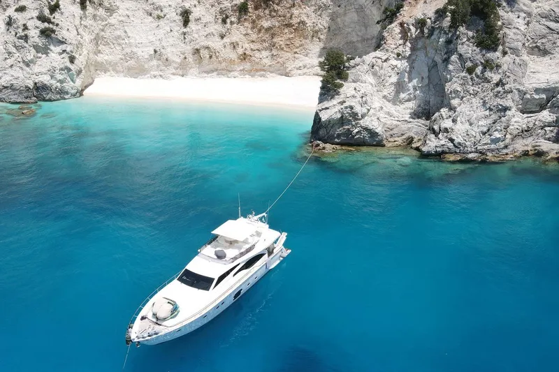 M/y Flow Yacht Photos Pics Luxurious 2008 Ferretti 681 yacht anchored in crystal-clear turquoise waters near rocky cliffs.