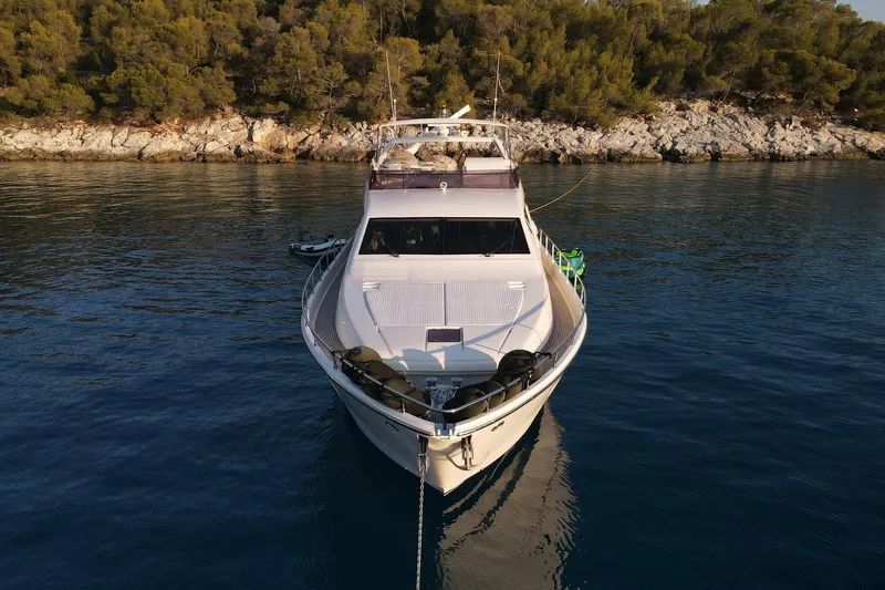 M/y Flow Yacht Photos Pics 2008 Ferretti 681 yacht anchored near rocky shoreline with lush greenery.